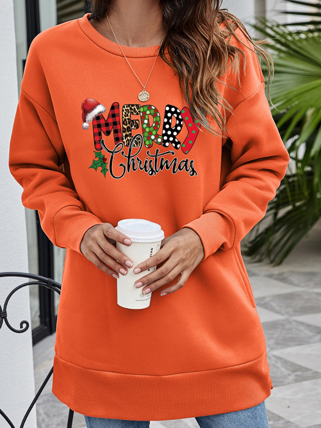 Orange-Red tunic sweatshirt with a festive "Merry Christmas" graphic featuring Santa hat, plaid, leopard, polka dot, and
