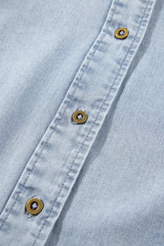 Light blue denim blouse with brass buttons and visible stitching detail.