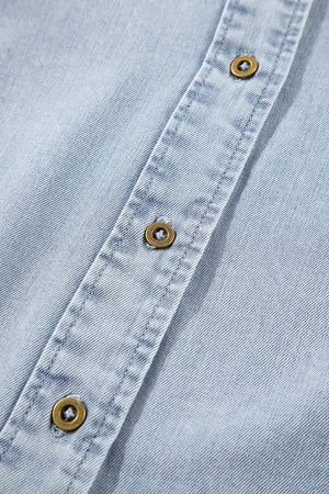Light blue denim blouse with brass buttons and visible stitching detail.