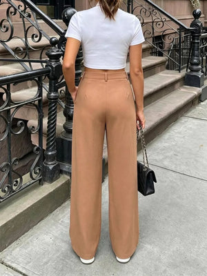 Brown pleated wide-leg pants with a belted waist, styled with a white crop top.