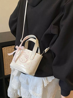 White mini crossbody bag with pink polka dots and Hello Kitty graphic, featuring a bow detail.