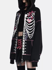Black zip-up hoodie with playful skeleton graphic, pink stitching, and drawstring hood.