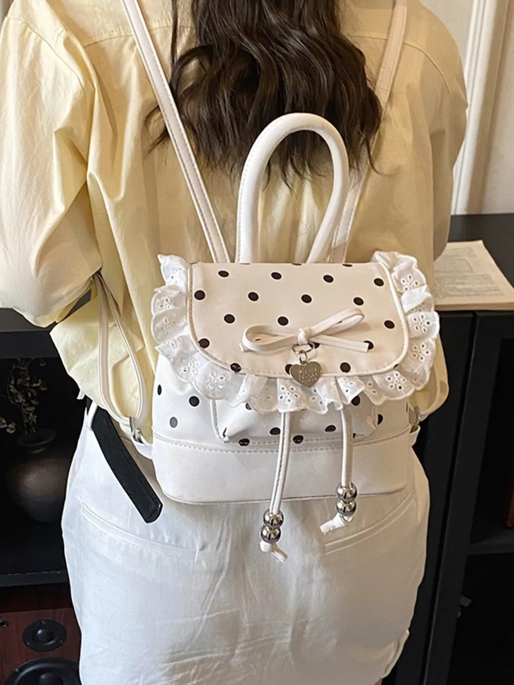 Charming polka dot lace mini backpack in cream white with bow detail and heart charm.