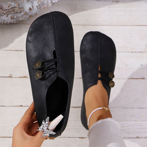 Black round-toe casual flats with decorative buttons and elastic detail.
