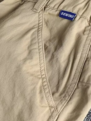 Khaki cargo pants with elastic waist and button closure, featuring a SEWING brand tag.