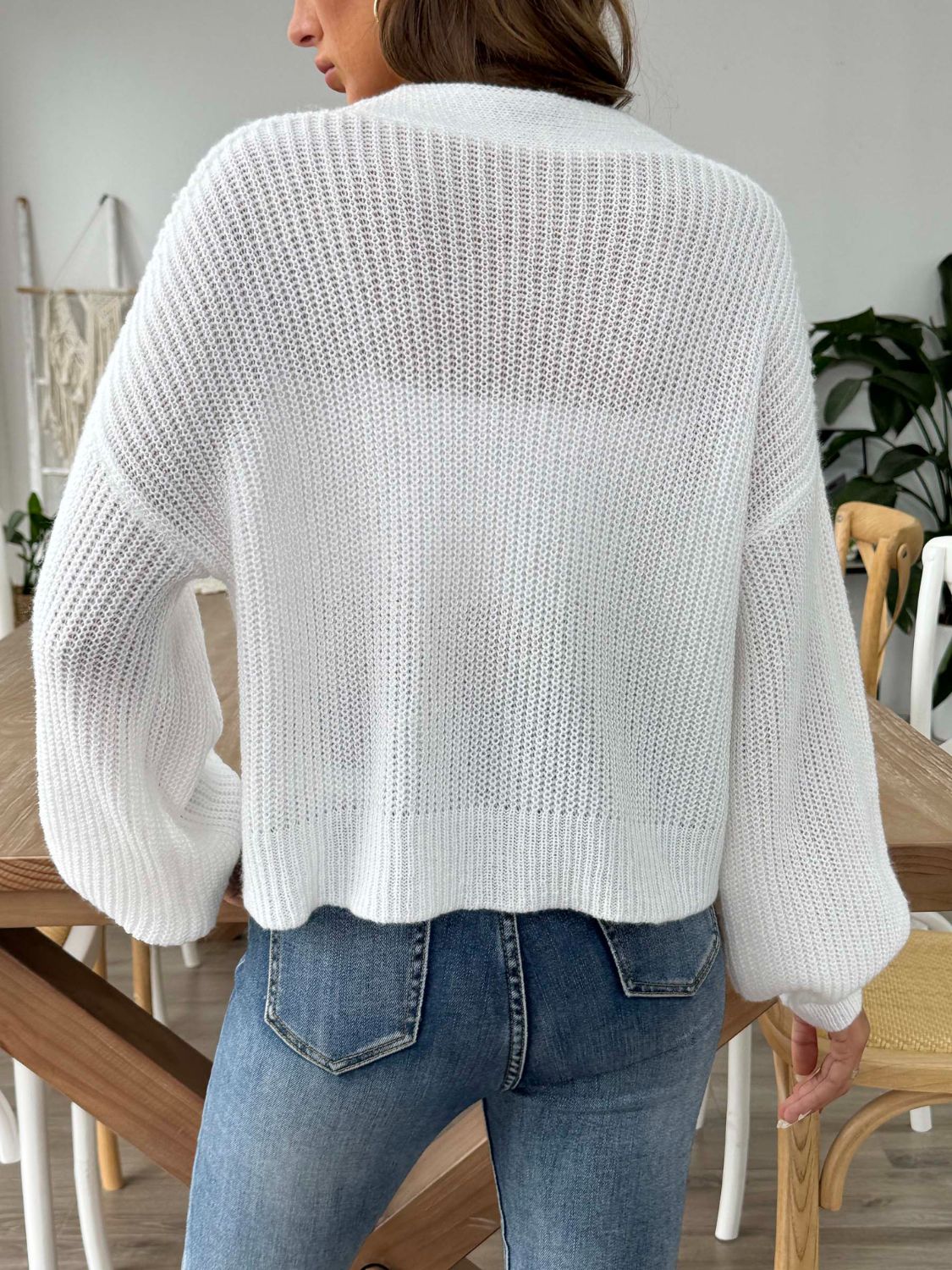 White balloon sleeve cardigan with a textured knit and button front, styled with jeans.