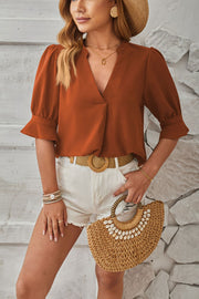 Brown puffed sleeve blouse with flared cuffs and v-neckline.