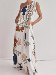 White one-shoulder maxi dress with abstract floral print and tie detail.