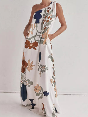 White one-shoulder maxi dress with abstract floral print and tie detail.