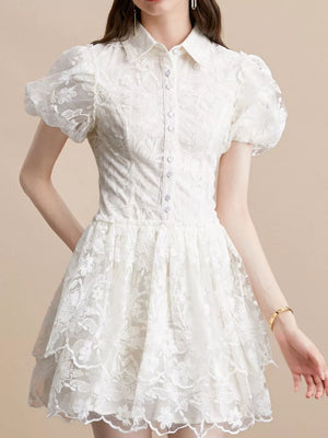 White lace mini dress with puff sleeves, button front, and tiered skirt.