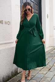 Green pleated maxi dress with V-neck, long sleeves, and wrap-tie waist.