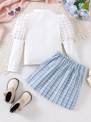 White puff sleeve top with textured sleeves and blue plaid skirt.