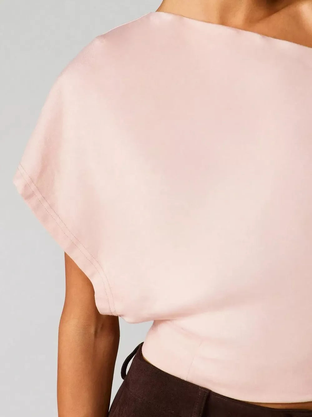 Pink asymmetrical crop t-shirt with draped fit and short sleeves.