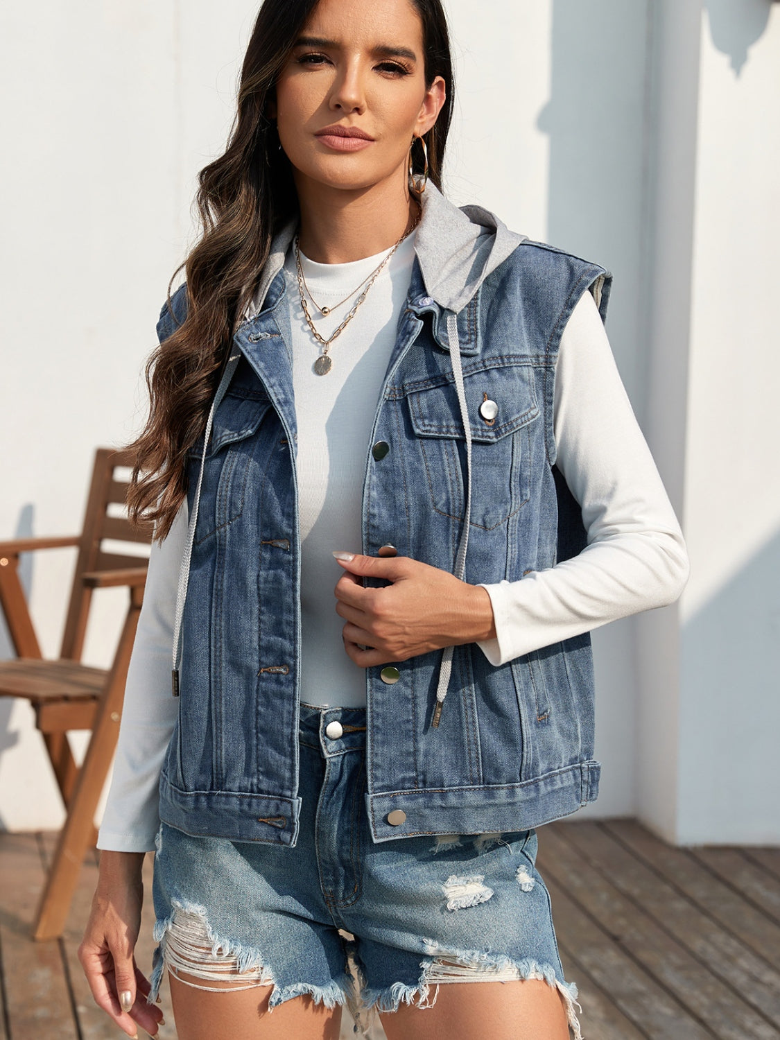 Sleeveless denim vest with hood detail in medium blue, buttoned front, and drawstring hood.