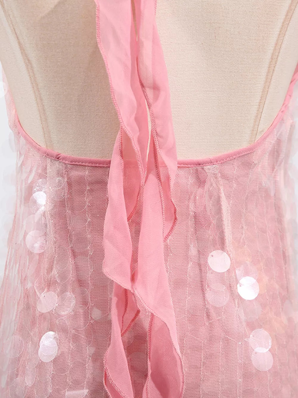 Pink iridescent sequin halter mini dress with ruffled trim and mesh overlay.
