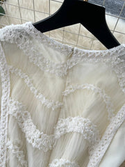 White tiered lace midi dress with textured trim and bow detail.
