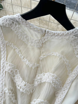 White tiered lace midi dress with textured trim and bow detail.
