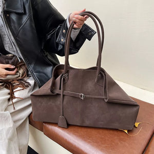 Brown suede tote handbag with decorative strap detail and double handles.