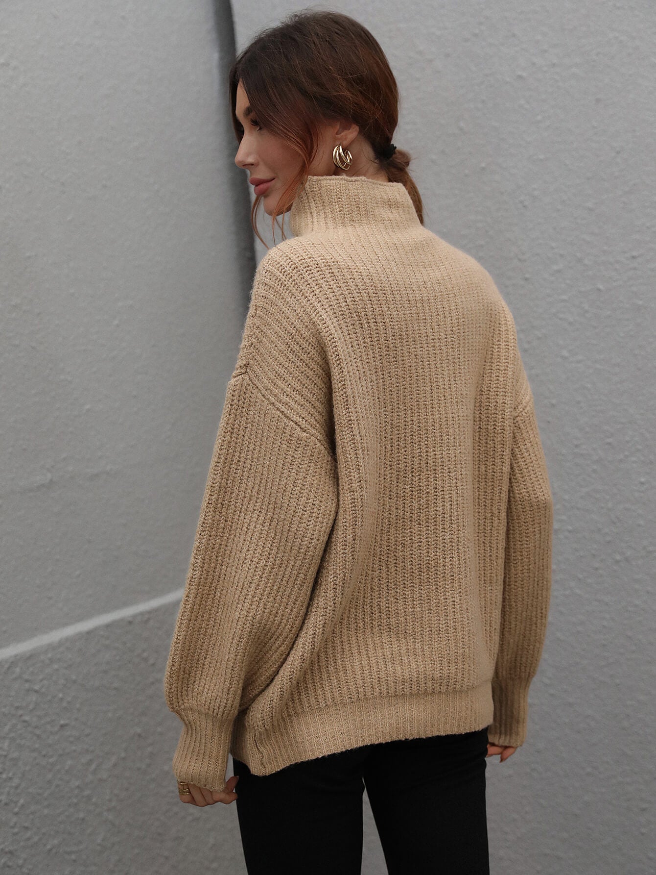 Tan ribbed knit turtleneck sweater with voluminous sleeves and a relaxed fit.