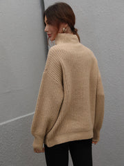 Tan ribbed knit turtleneck sweater with voluminous sleeves and a relaxed fit.