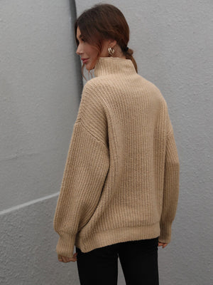 Tan ribbed knit turtleneck sweater with voluminous sleeves and a relaxed fit.