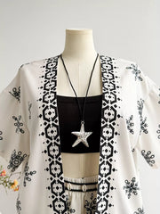 White polyester kimono jacket with black geometric and floral print, worn over a black crop top and shorts.