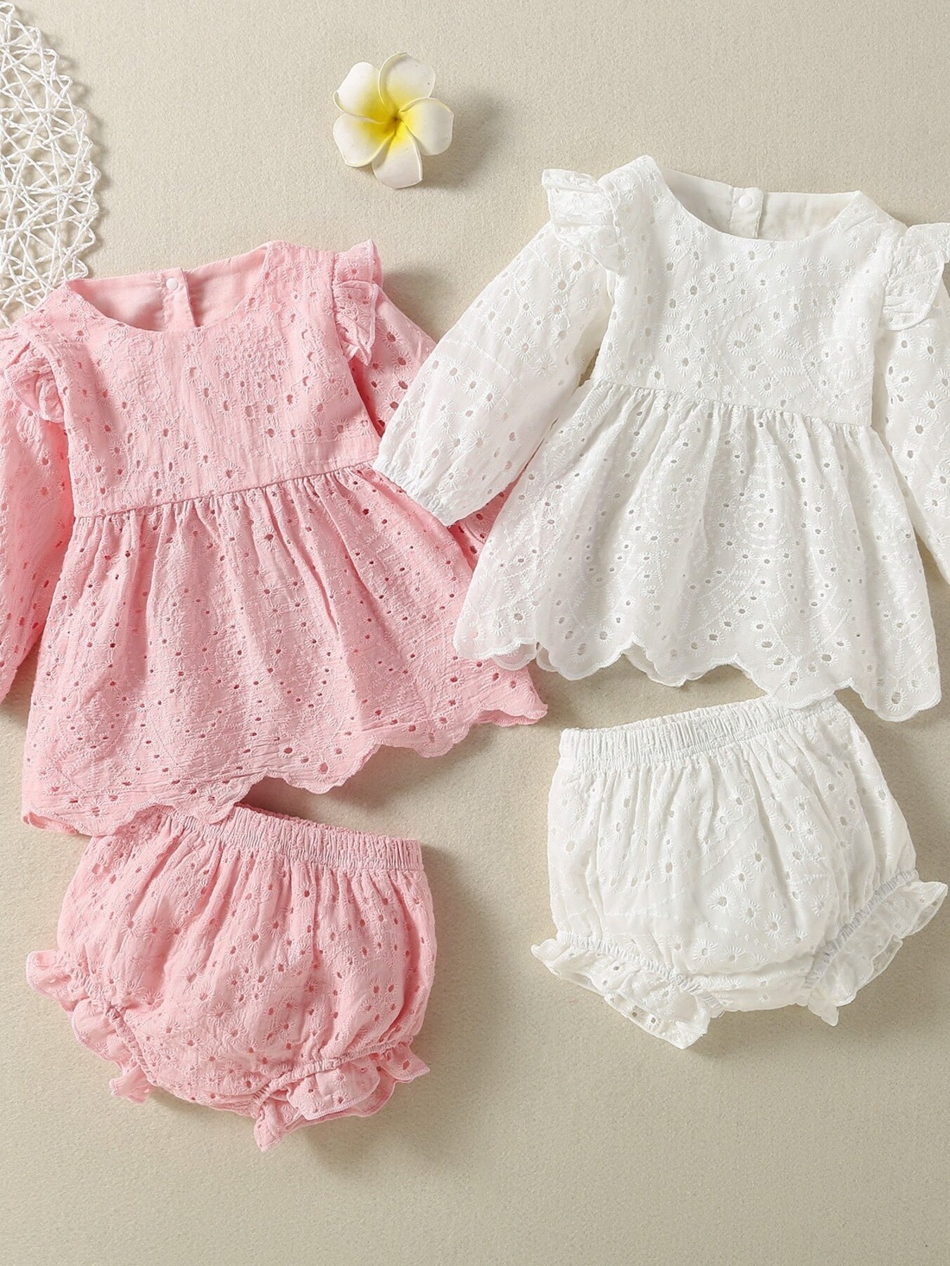 Embroidered lace baby top and shorts set in white and pink with ruffled details.