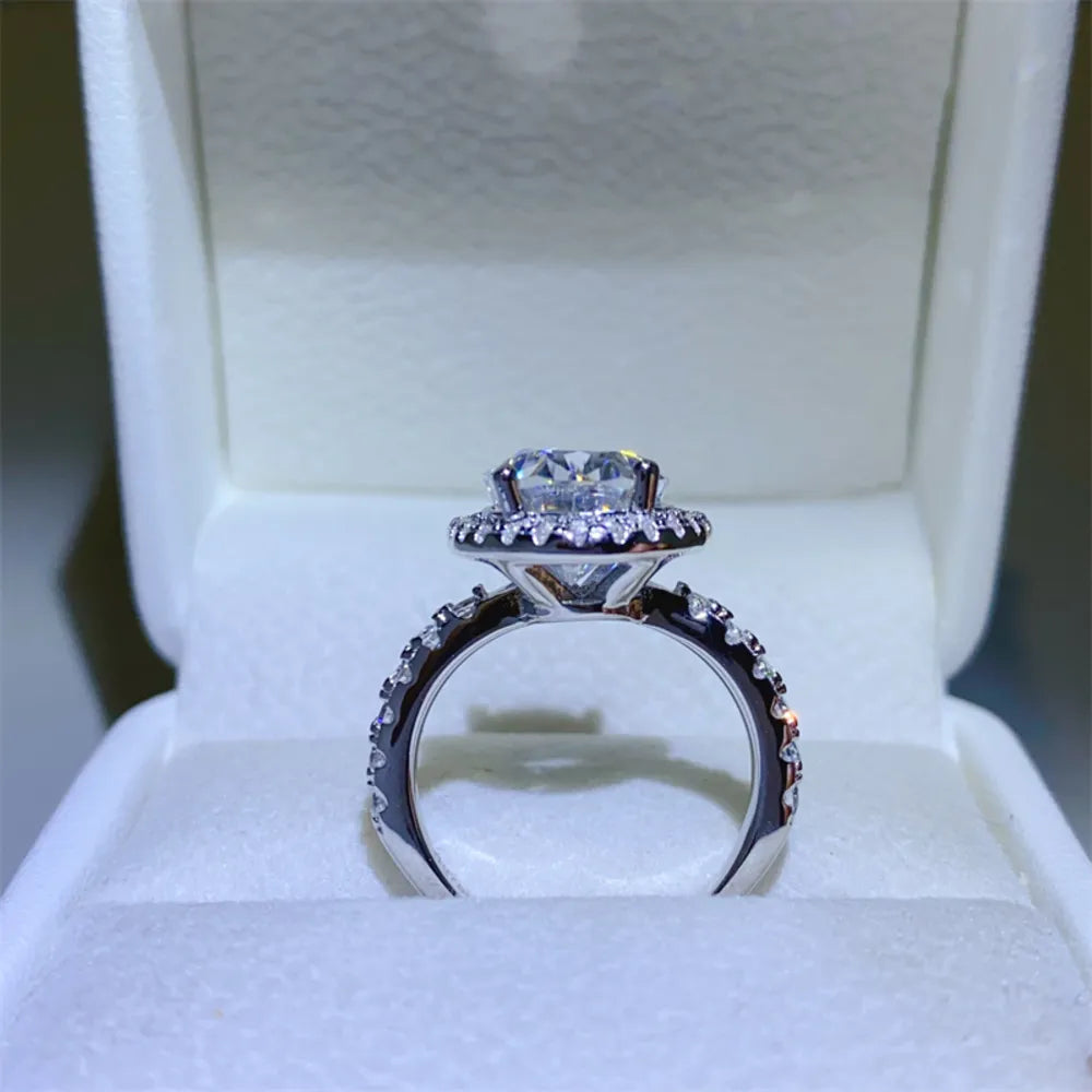 Silver oval halo moissanite engagement ring with pavé band.