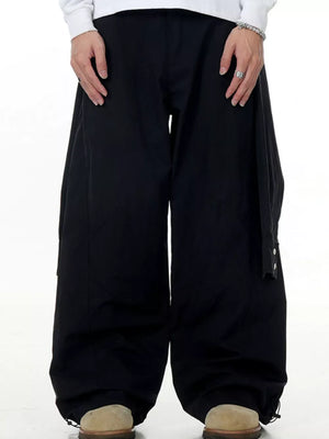 Black wide-legged cargo pants with buttoned pockets and drawstring cuffs.