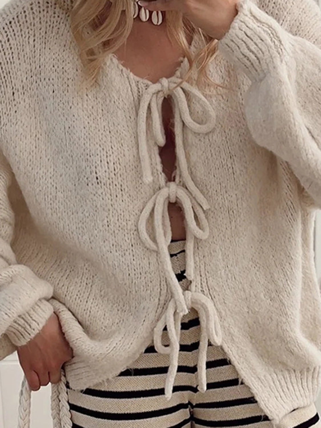Beige knit cardigan with balloon sleeves and lace-up front detail.