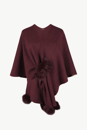 Wine knit cape with fur trim detail and pom poms.