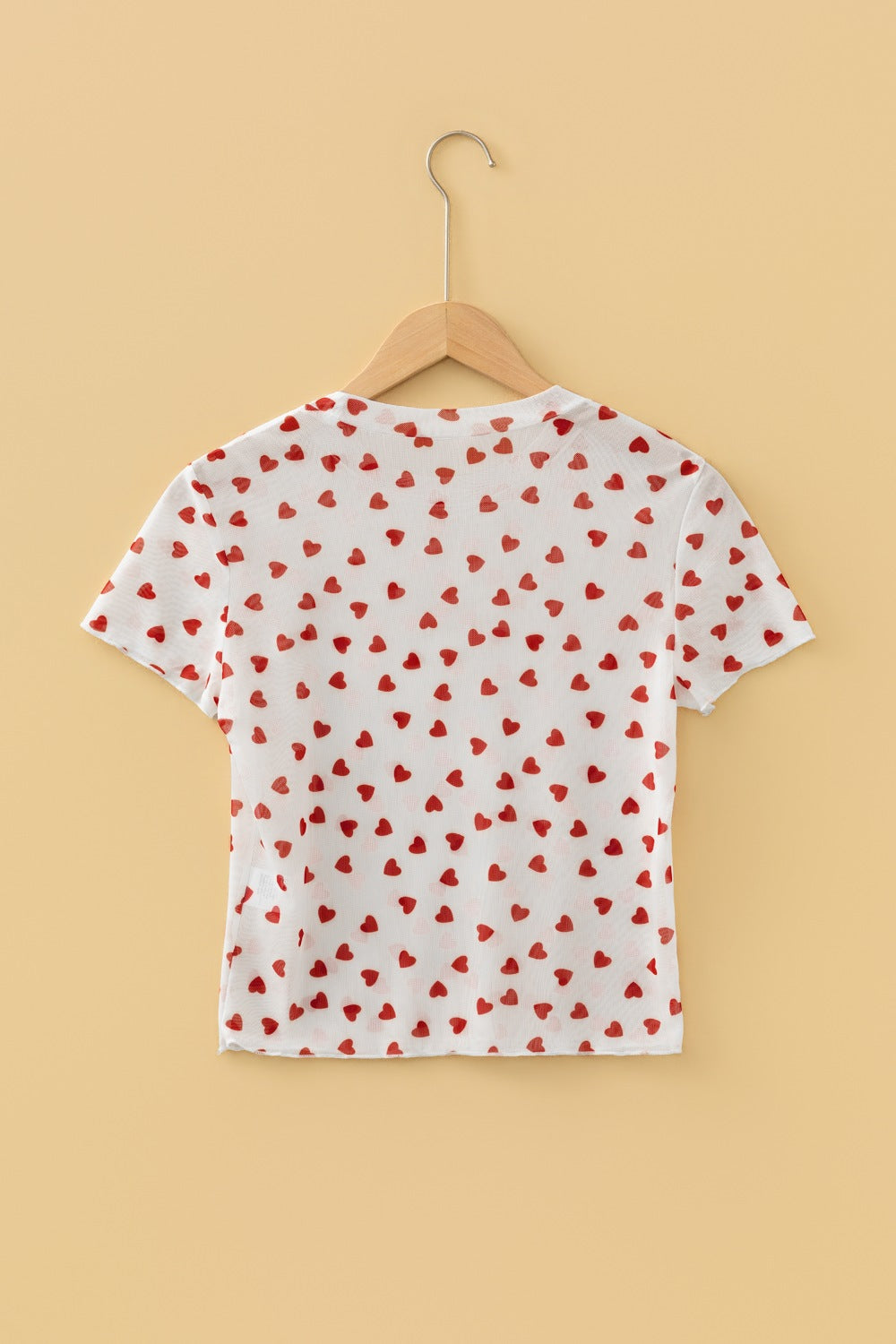 White sheer t-shirt with all-over red heart print, short sleeves, and a cropped fit.