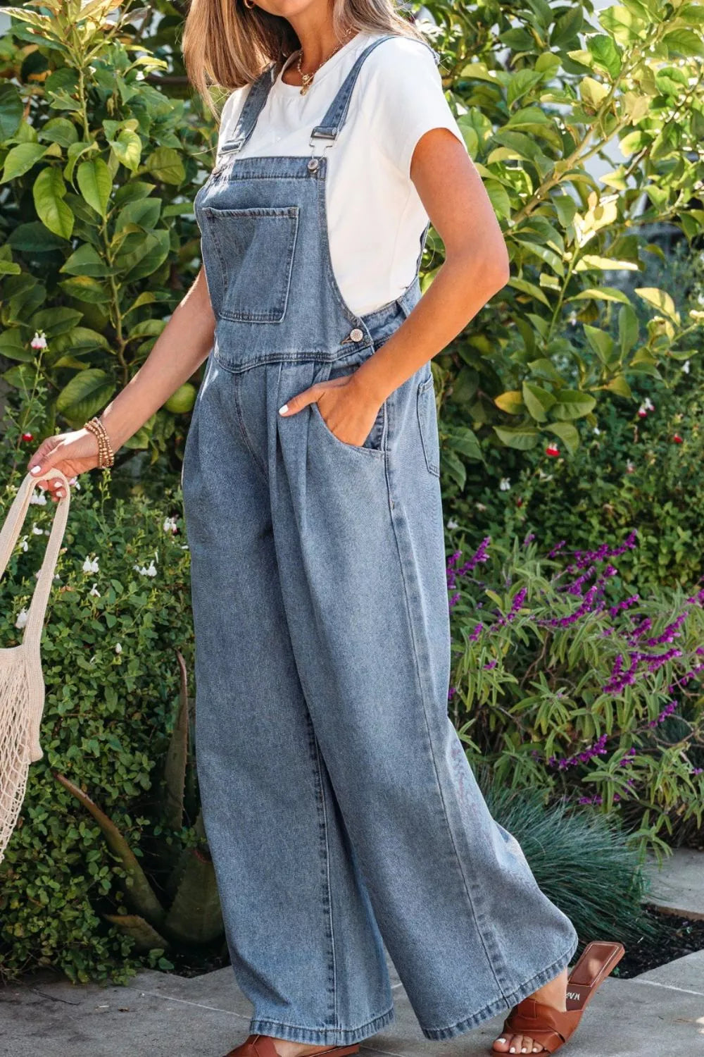 Denim wide-leg jumpsuit with pleats and buttons, styled with a white tee.