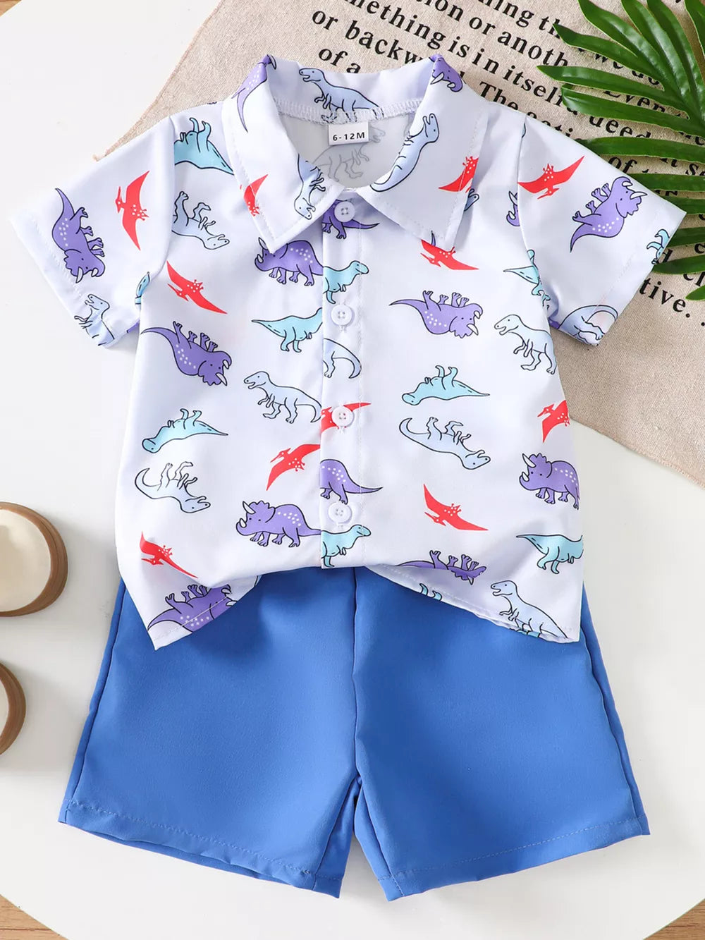 Toddler blue shorts and white short-sleeve button-up shirt with dinosaur print