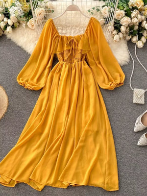 Yellow maternity dress with square neck, ruffled detail, smocked bodice, balloon sleeves, and A-line skirt.