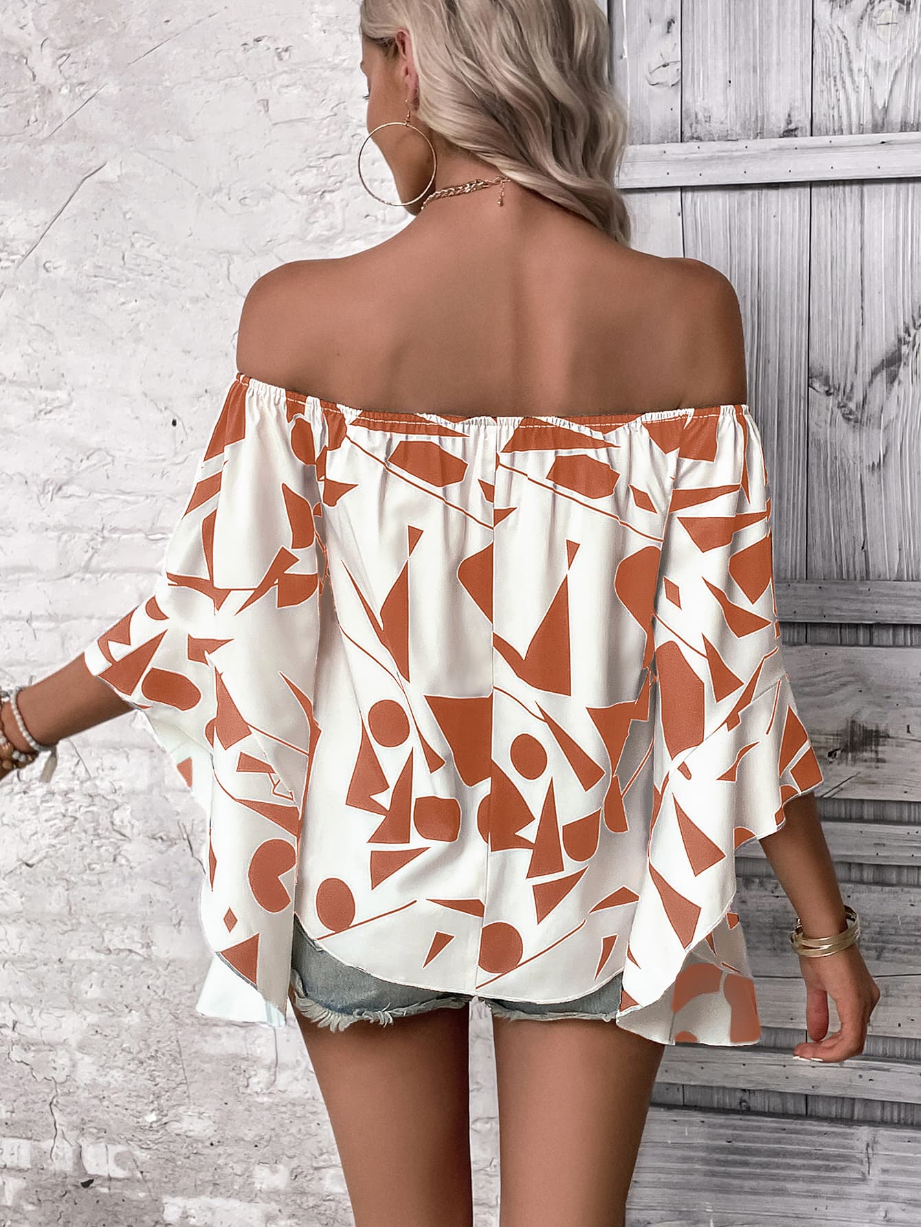 Geometric print off-shoulder blouse with flared sleeves in white and orange.