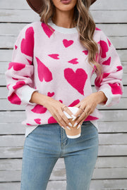 Pink intarsia knit jumper with allover heart pattern and white cuffs.