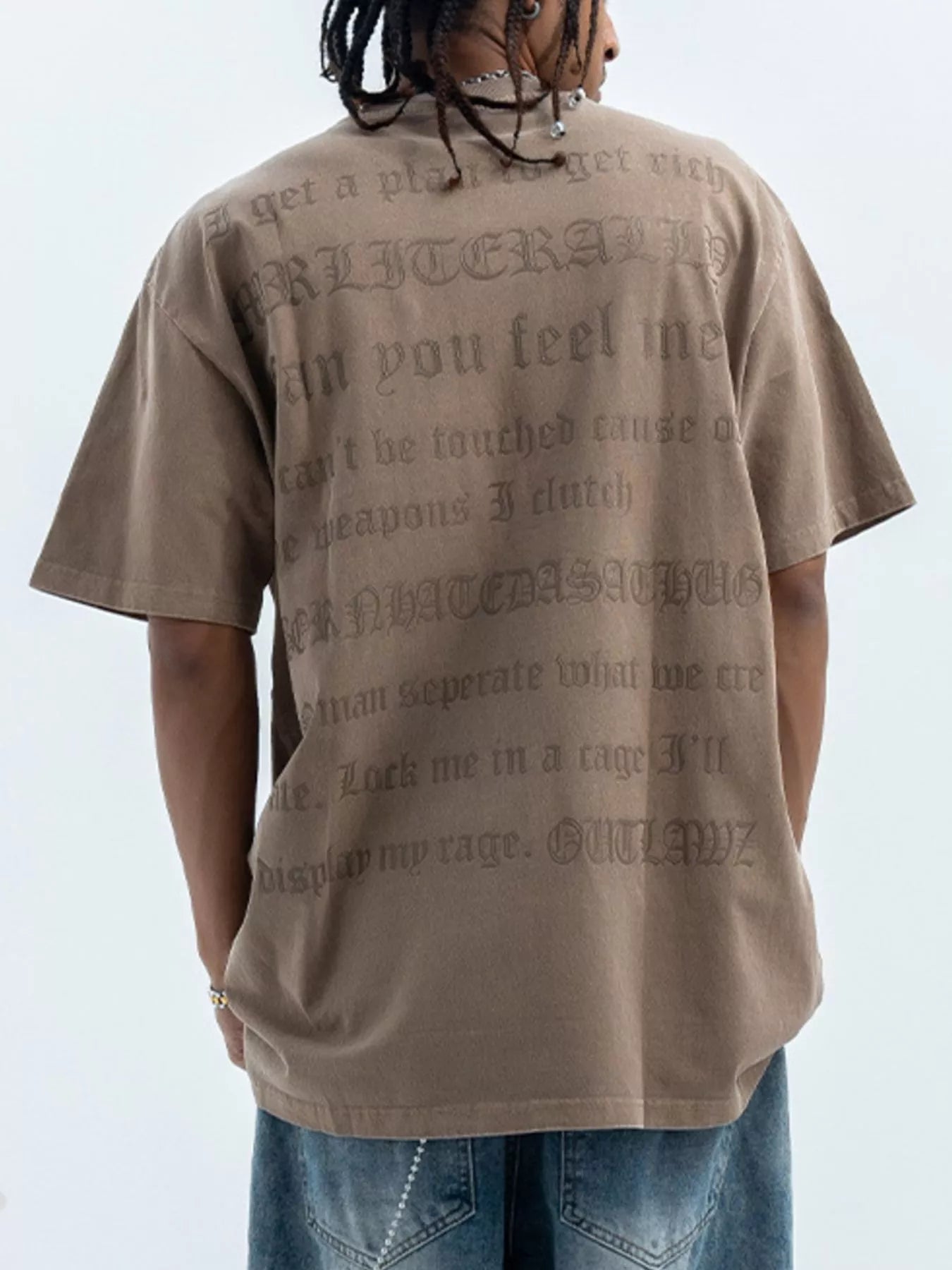 Brown oversized graphic tee with embossed text on back, 100% cotton.