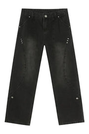 Dark wash denim jeans with asymmetric seams and silver stud details.