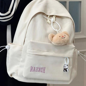Off-white nylon backpack with front pocket, bear charm, and panda keychain.