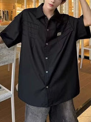 Black relaxed fit oversized button-up shirt with chest pleats and buttoned pockets.