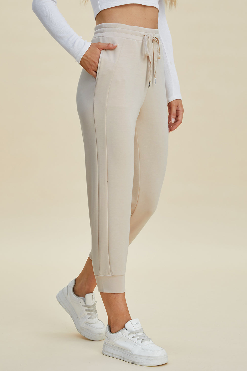 Beige joggers with drawstring waist and side seam detail.