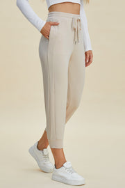Beige joggers with drawstring waist and side seam detail.