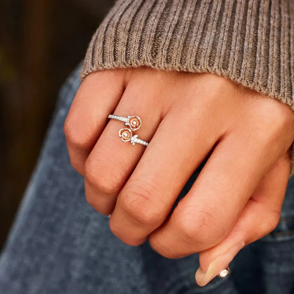 Silver bypass ring with rosebud details and pavé accents on a hand.