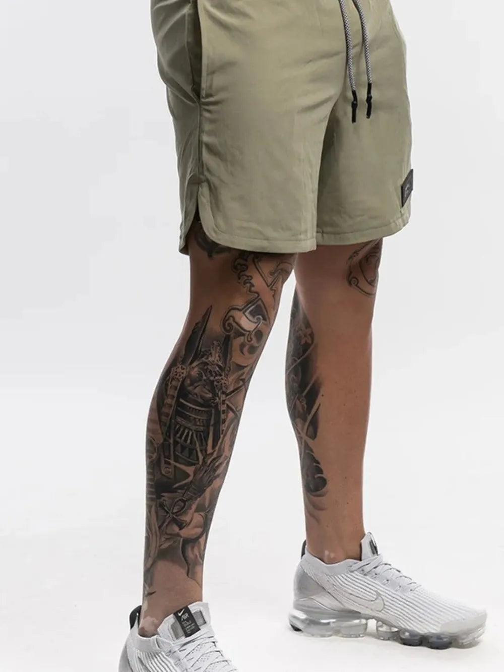 Khaki performance shorts with drawstring and logo patch, showing side slit detail.
