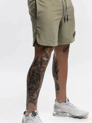 Khaki performance shorts with drawstring and logo patch, showing side slit detail.
