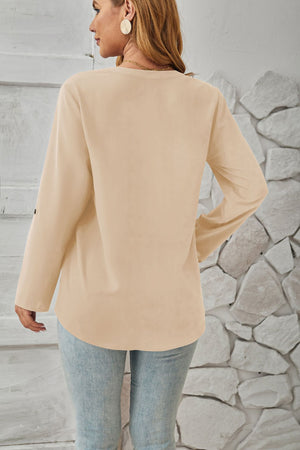 Ivory V-neck blouse with cuffed long sleeves and button detail on sleeve.