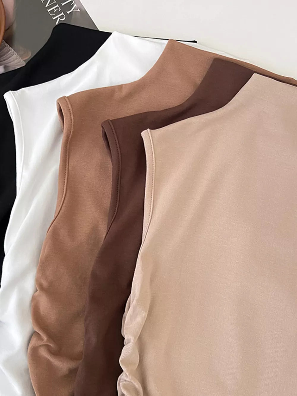 Textured ruching mock neck tank top in brown, white, and black with draped detail.