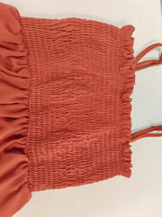 Orange-red smocked romper with ruffle trim and adjustable straps.