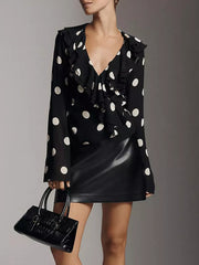 Black polka dot sheer v-neck blouse with ruffles and long sleeves.